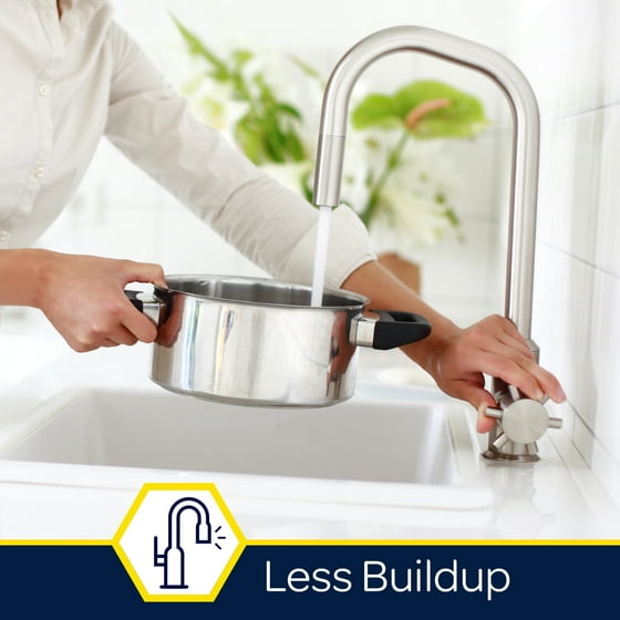 Person washing a pot under a faucet with a 'Less Buildup' icon in the corner.